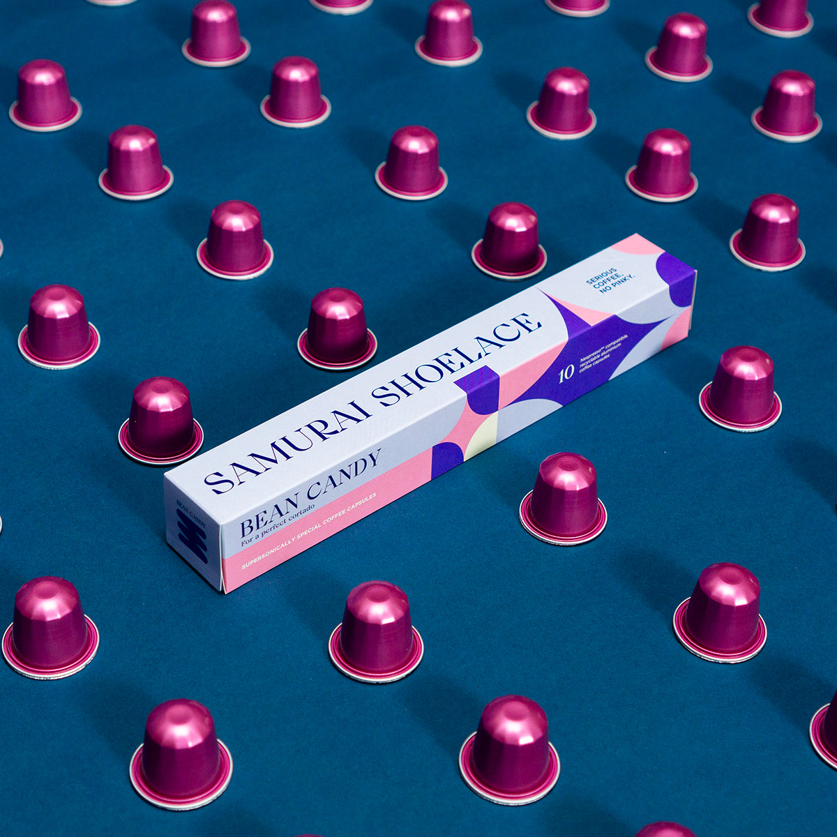 Samurai Shoelace Serious Coffee Bean Candy kávékapszula termékfotója lila háttérrel rózsaszín kapszulákkal cortado üvegpohárban