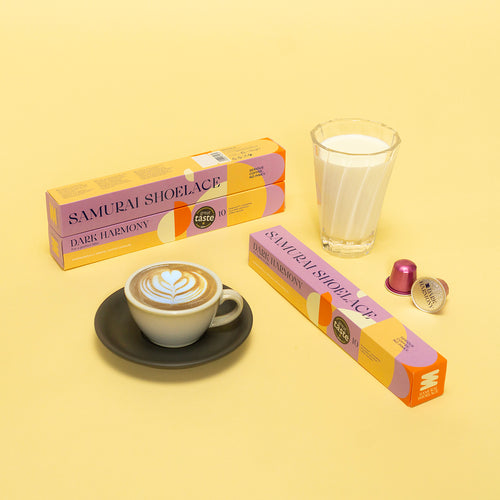 Samurai Shoelace Serious Coffee Dark Harmony kávékapszula termékfotója sárga háttérrel minimalista elrendezésben latte csészével